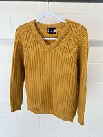 Front view of mustard yellow knit sweater on hanger
