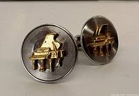 Front view of both cufflinks showing piano motif and record grooves