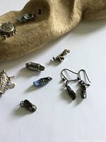 Overall view showing stein charm, rectangular charm, two blue enamel shoe charms, plain shoe charm, revolver and earrings