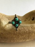 Front view of silver ring with four turquoise cabochons in diamond cluster