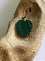 Front view of apple-shaped malachite pendant on wood prop