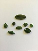 Eight polished jade cabochons on white background