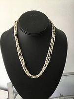 Necklace on display form showing triple strands and bead accents