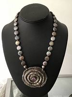 Necklace on display bust showing overall appearance, coin pearl strand and large spiral pendant