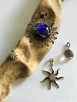 Group shot showing all four pendants on driftwood and paper background