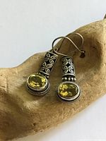 Front view of earrings showing yellow stones and silver design