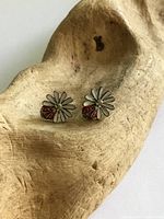 Front view showing daisy shape, enamel petals, ladybug accents