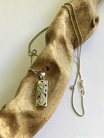 Pendant and chain draped on driftwood showing full necklace