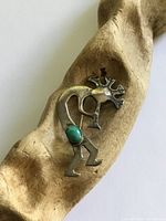 Front view of sterling Kokopelli brooch on wood prop