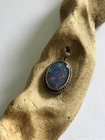 Full view of pendant on driftwood showing stone and setting