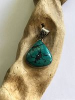 Front view of turquoise pendant on wood prop