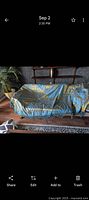 Full view of gold and blue damask bedspread displayed on a sofa
