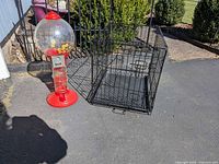 gumball machine beside wire dog crate on driveway