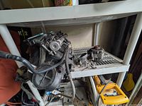 Overall view of intake/carburetor assembly on shelf with alternator beside it