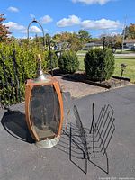 Walnut smoked lucite lamp beside black wire magazine rack outdoors