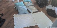 Group shot of five throw pillows and two white quilted shams laid on floor