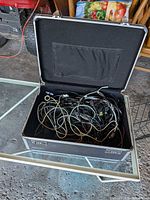Open metal suitcase showing numerous tangled cables