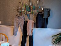 Group shot of five garments hanging: patterned pants, tan linen pants, black faux leather pants, black button skirt, folded olive skirt