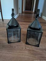 Two black metal square lantern lights on floor