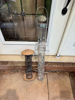 Both bird feeders leaning against a door for scale