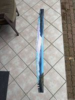 Full view of painted crosscut saw blade on tiled floor