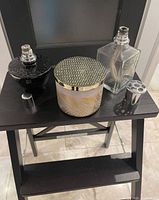 Black textured lamp, clear glass lamp, candle with lid on small stand