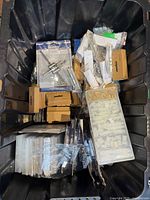 Overview of tote containing various boxed, bagged and cased hardware items