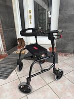 Side view of black Nexus rollator showing seat, wheels, hand brakes, overall condition