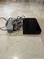 Top view of black Nintendo Wii console with attached AC adapter and AV cable