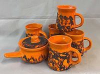 Group shot of five mugs and lidded soup bowl