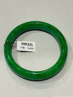 Green jade bangle with price tag showing Chinese text