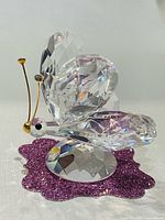 Front side view of Swarovski crystal butterfly figurine on purple surface