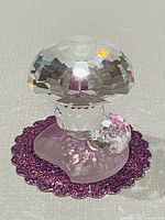 Front view of Swarovski crystal mushrooms on purple glitter disc