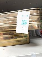 Two brass rectangular trays stacked on shelf showing ribbed sides and patina