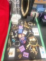 Full lot overview showing necklaces, earrings, bangles and bracelets laid out on black cloth with display stands