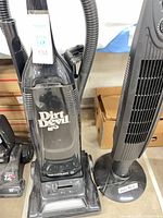 Dirt Devil Toughmate 11 upright bagless vacuum cleaner next to black tower electric heater
