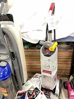 Hoover SmartWash carpet cleaner with hose, attachments and Eureka bagless vacuum adjacent