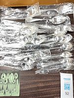 sealed stainless flatware pieces and Oneida booklet on table