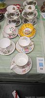 Overall lot view showing multiple stacked tea cup and saucer sets