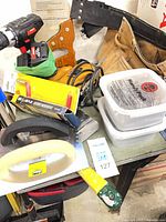 Overall view of assorted tools including drill, jigsaw, tool belt, saw handle, float, sanding block, packaged blades and containers