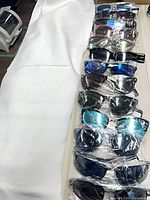 Row of approximately 13 individually wrapped sunglasses with various frame and lens colors