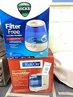 Box of Vicks filter-free cool mist 4.5 L humidifier stacked on ReliOn warm moisture 7.6 L humidifier box