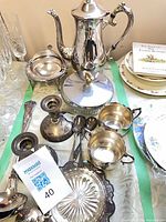 Group shot showing majority of sterling pieces, candlesticks, spoons, glass dish and tray