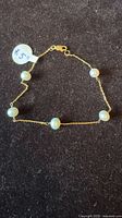 Full view of gold bracelet with five pearls laid flat