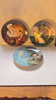 Front view of three Disney plates: Geppetto & Pinocchio, Cinderella cleaning, Blue Fairy & Pinocchio