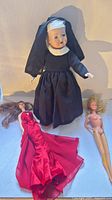 Group shot of bisque doll in nun habit with two Barbie dolls