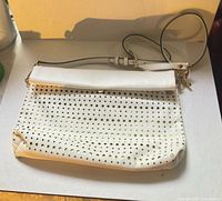 Front view of white perforated Michael Kors crossbody bag with strap visible