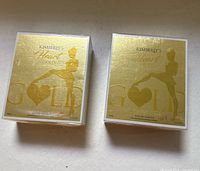 Front view of both sealed perfume boxes showing branding and gold packaging