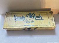 Top view of closed Handy Andy yellow metal toolbox showing logo