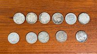 Front view of all eleven coins laid out on wood surface